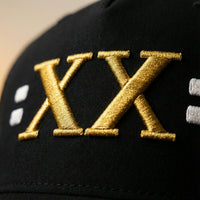 Close-up gold XX embroidery detail on Jamal Roberts Midnight Slate American made trucker hat