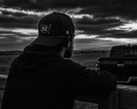 Black-and-white portrait of USA 250 being worn beside a truck.