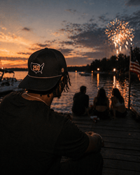 USA 250 being worn beside a lake with fireworks in the background.