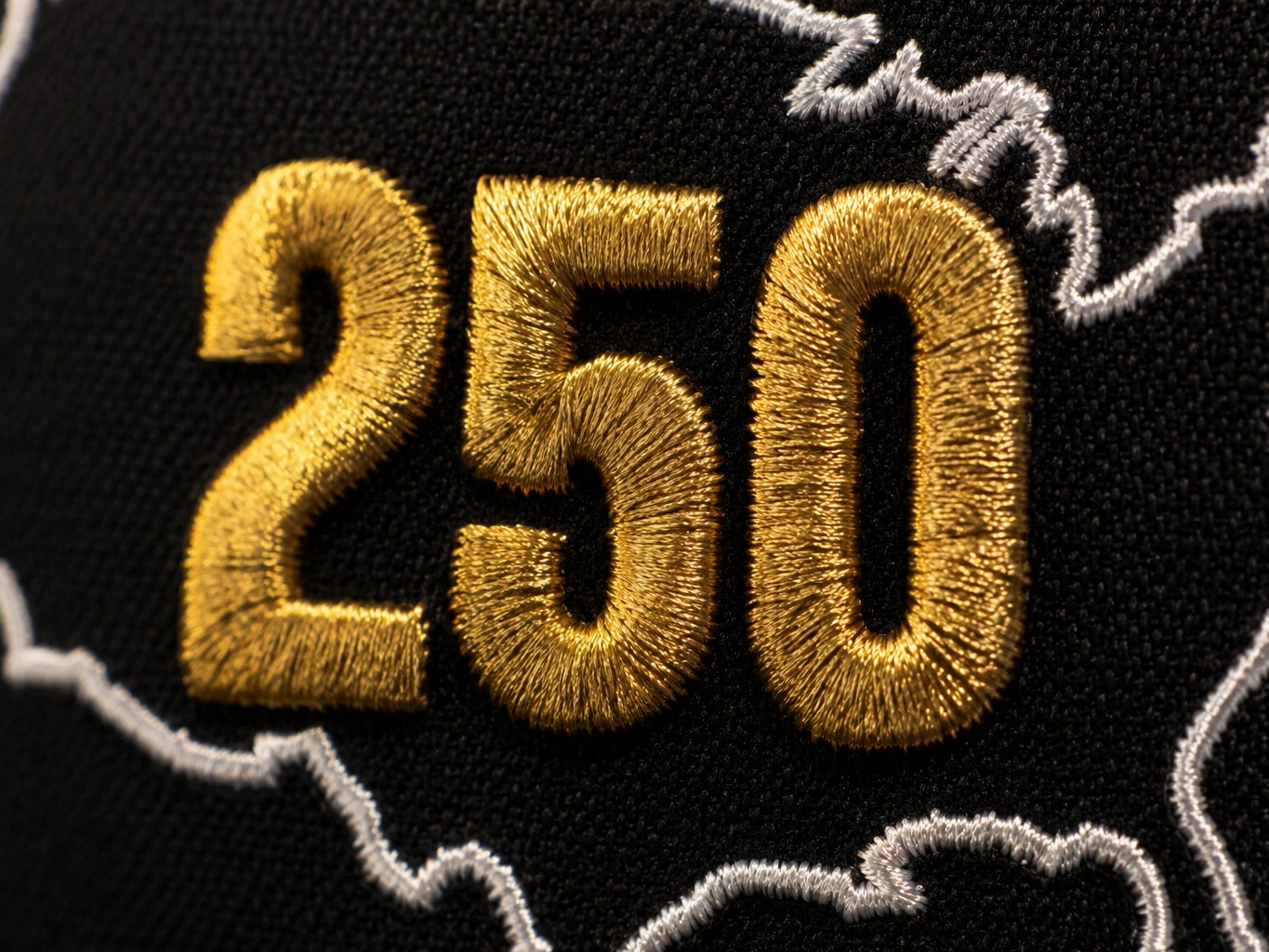 Macro of the raised gold 250 embroidery on the USA 250 snapback front panel