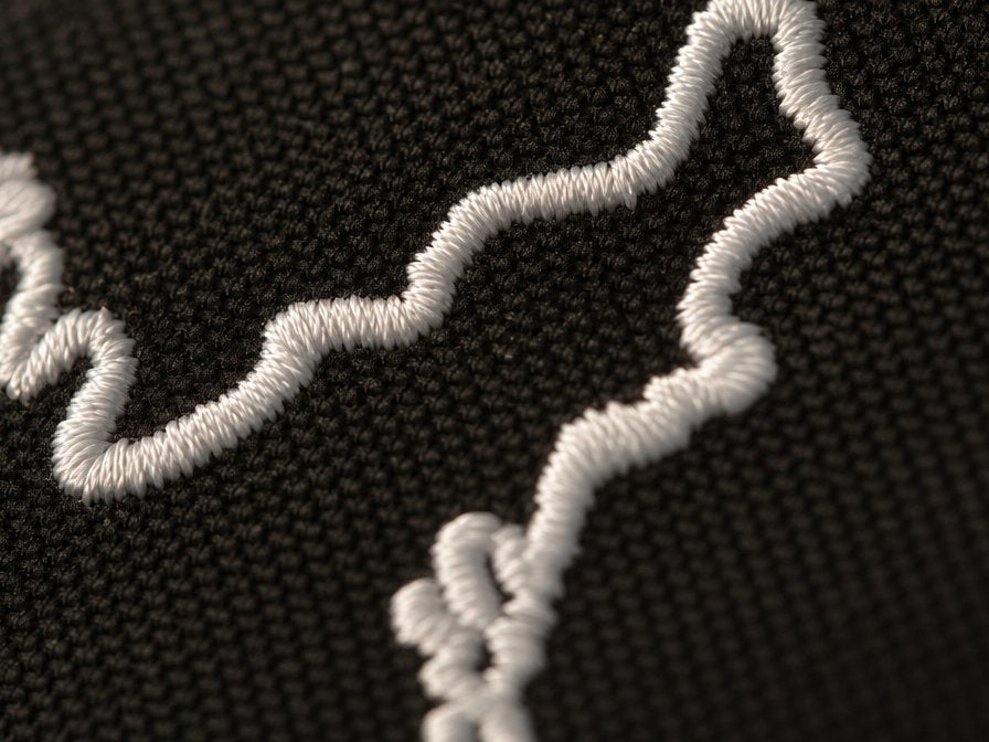 Macro of the white embroidered USA contour stitching on the USA 250 snapback