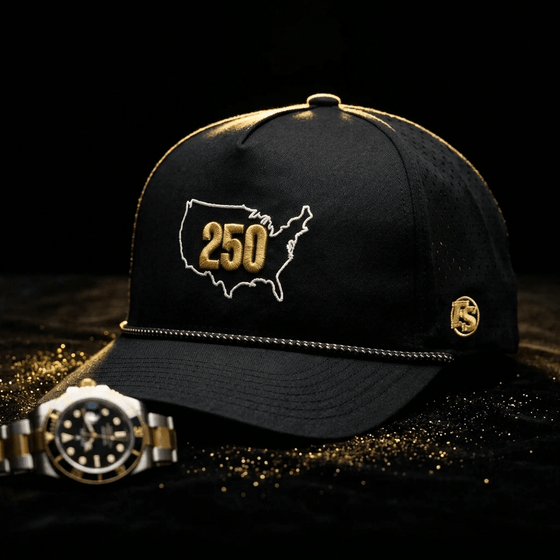 USA 250 on a dark table beside a watch, with a white US outline, gold 250, gold FS badge and perforated panels.